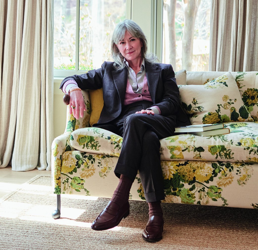 Portrait of Colleen DeCourcy sitting on a floral sofa.