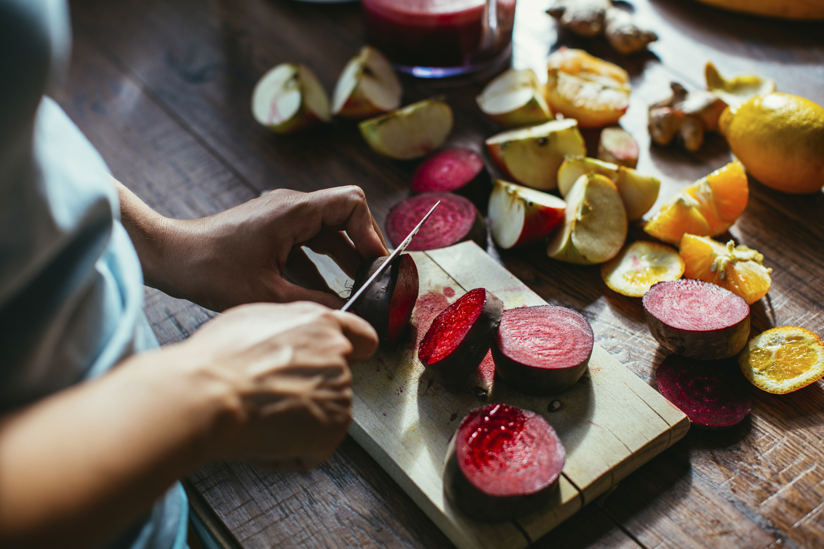 Woman's hands chopping beetroot on a cutting board.