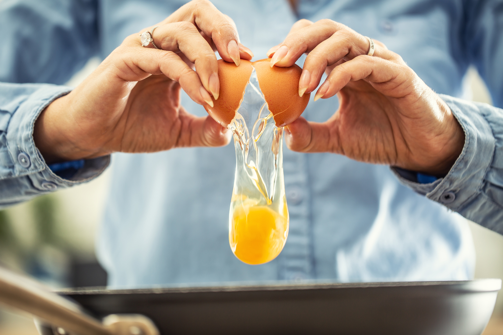 Person cracking an egg into a pan.