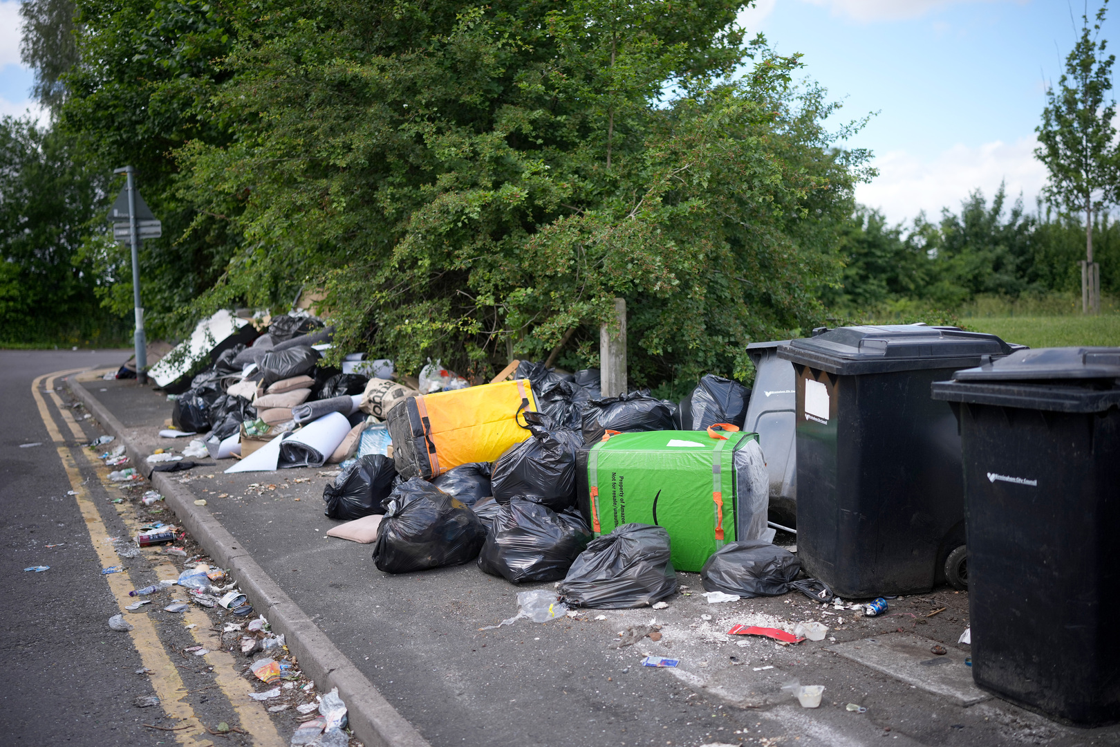 Overflowing bins and rubbish bags on a Birmingham pavement due to refuse workers' strike.