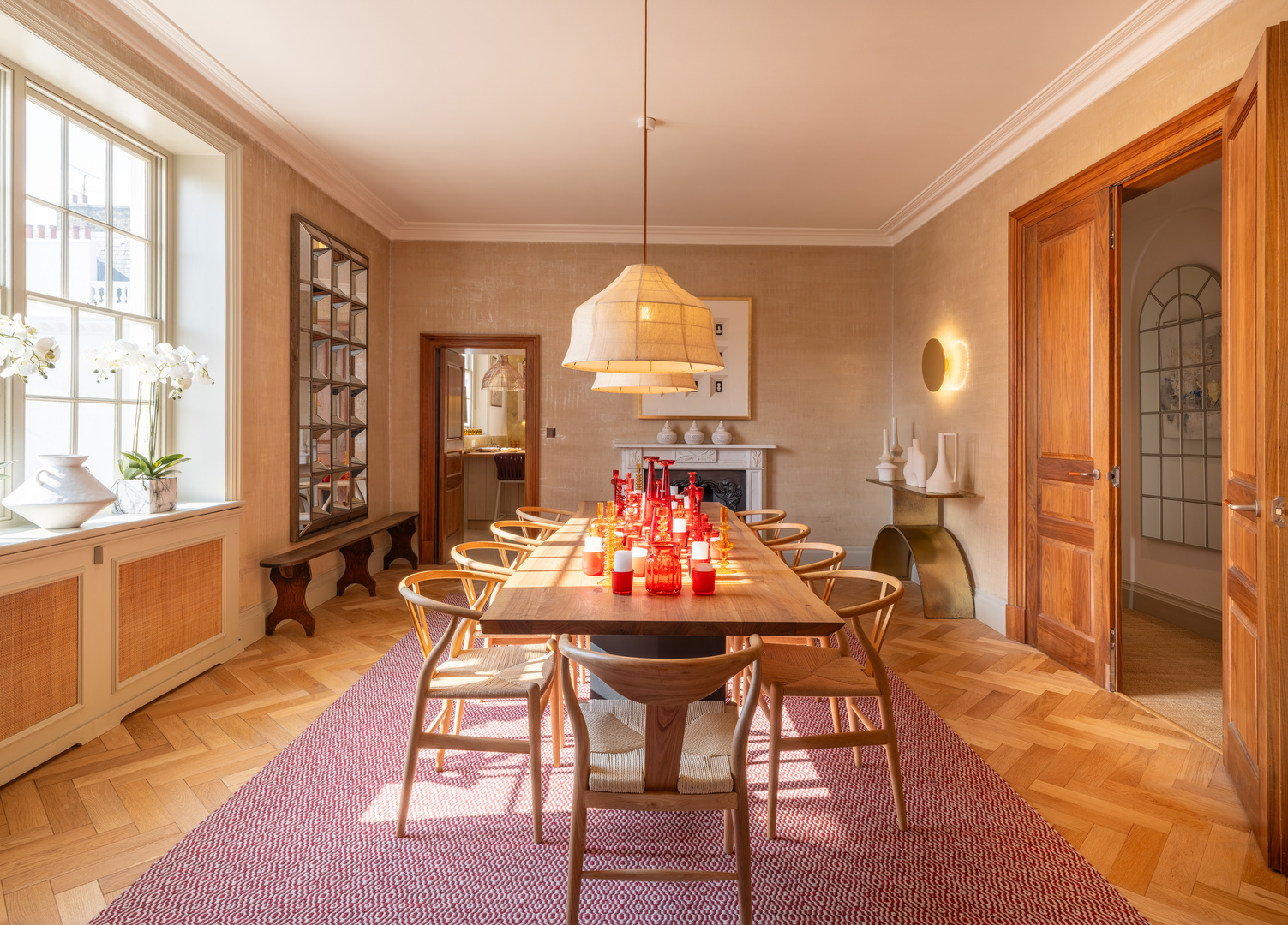 Interior view of a dining room with a large wooden table, chairs, and red and orange decorations.
