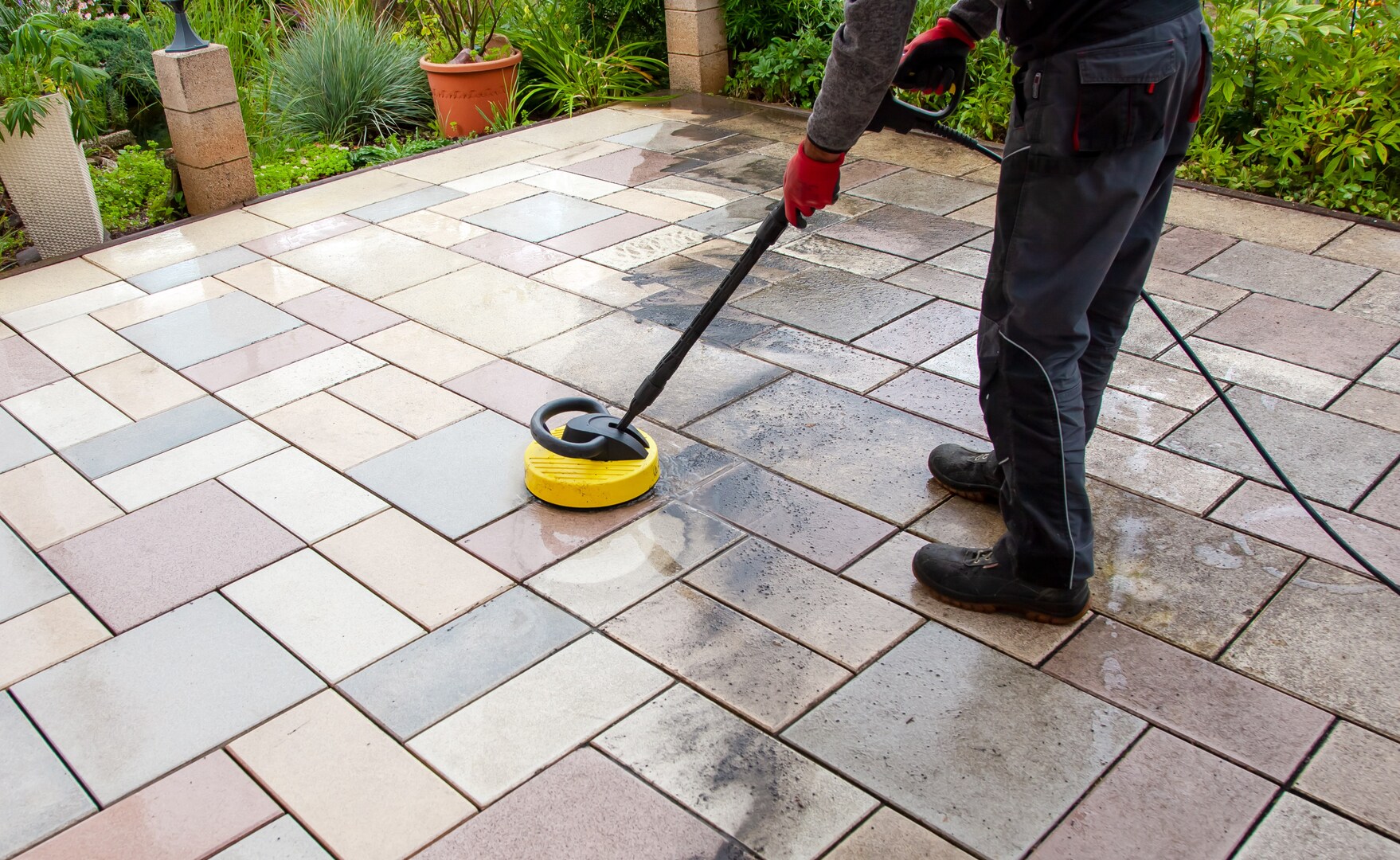 Person pressure washing patio stones.