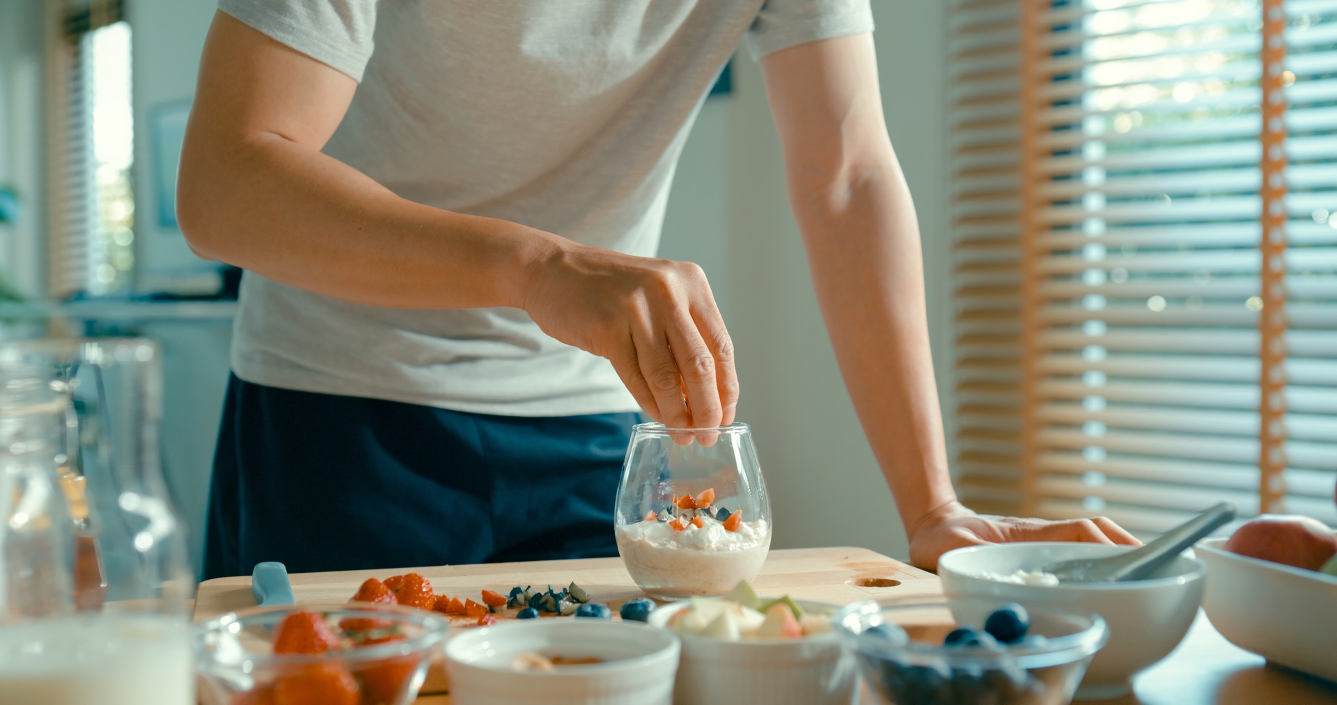 A person preparing yogurt and muesli for breakfast.