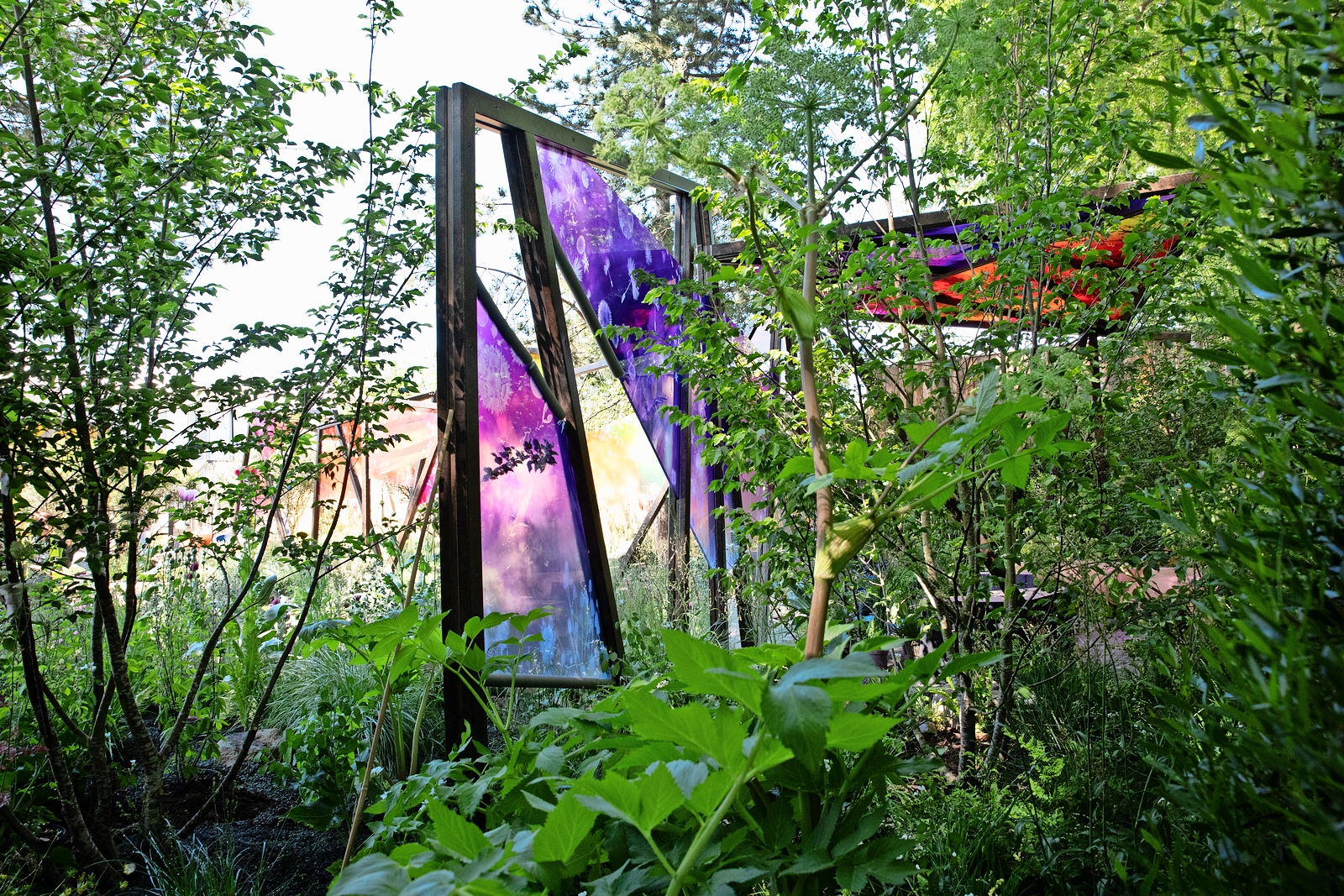 Chelsea Flower Show garden with purple and orange stained-glass panels.