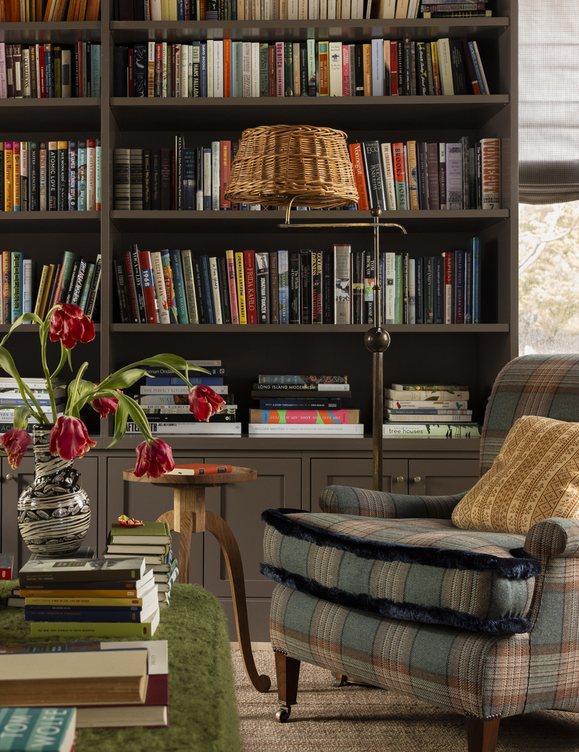 A library with bookshelves, armchair, and a side table with tulips.