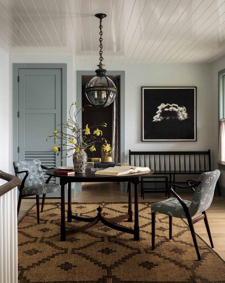 Entrance hall with pale blue walls, a round table, chairs, and a large black and white photograph of a cloud.