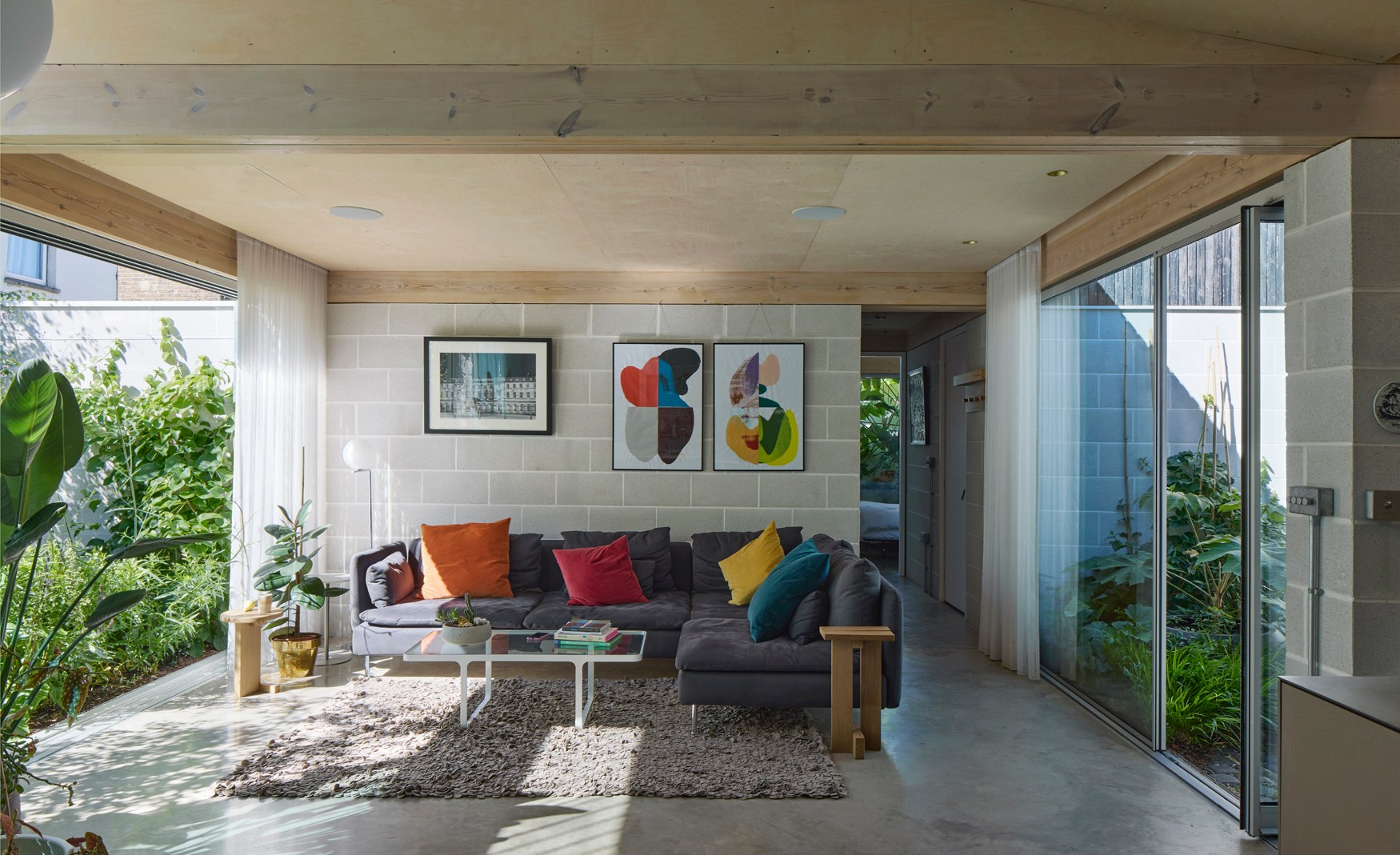 Living room with gray sectional sofa, artwork, and garden view.